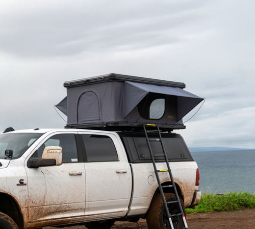 Hardshell pop-up rooftop tent mounted on a truck with ladder deployed